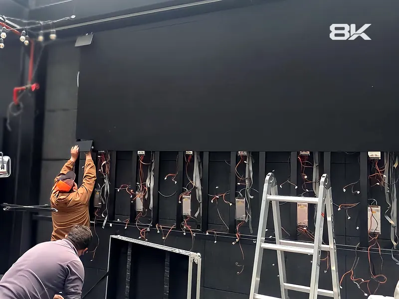 Técnicos de 8K instalando los módulos de un muro LED con escalera y cableado
