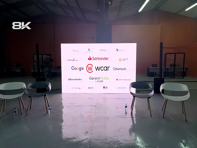 Set de conversatorio con sillas y una pantalla LED con logos de patrocinadores