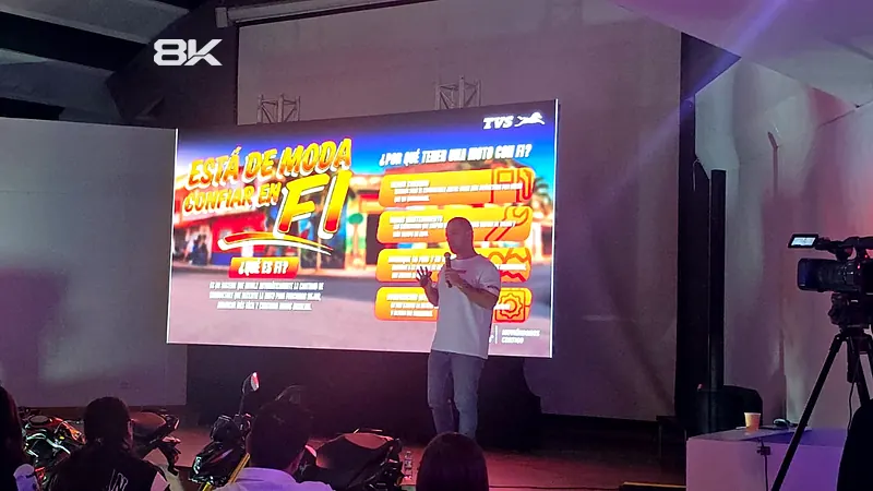 Presentador frente a una pantalla LED con cámara de video grabando el evento