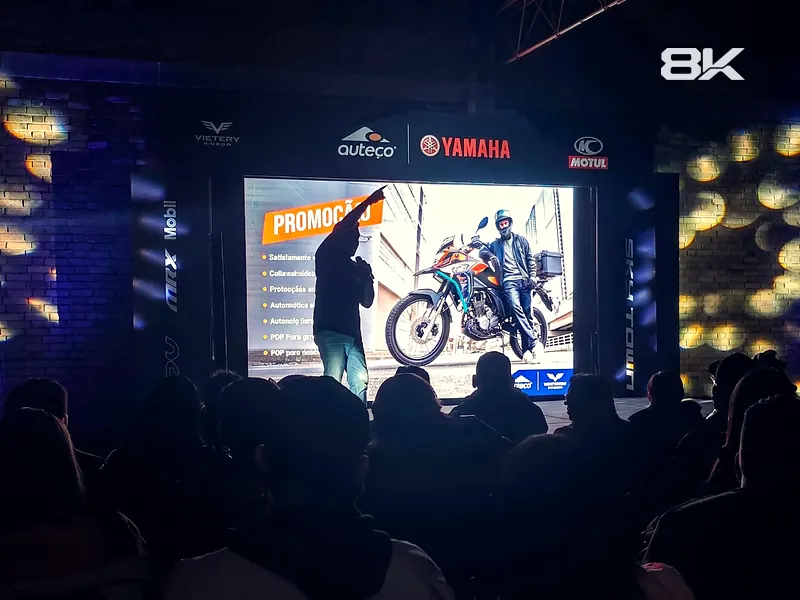 Presentación en un concesionario de motos con pantalla LED y público