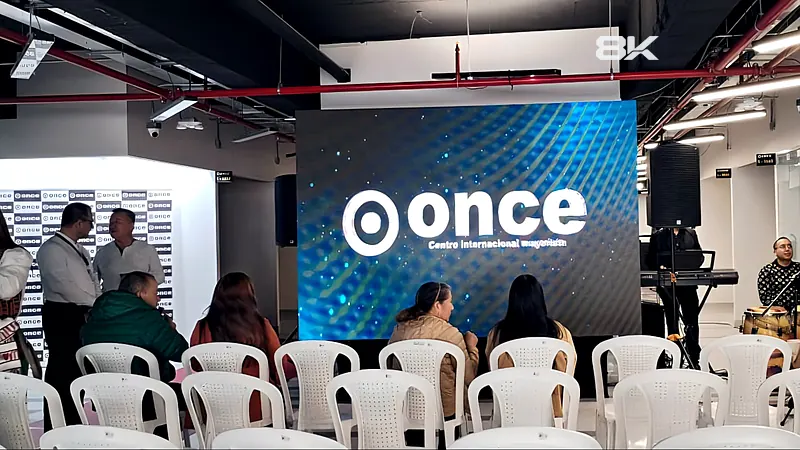 Pantalla LED con la marca del evento, sillas para el público y músicos en un lanzamiento