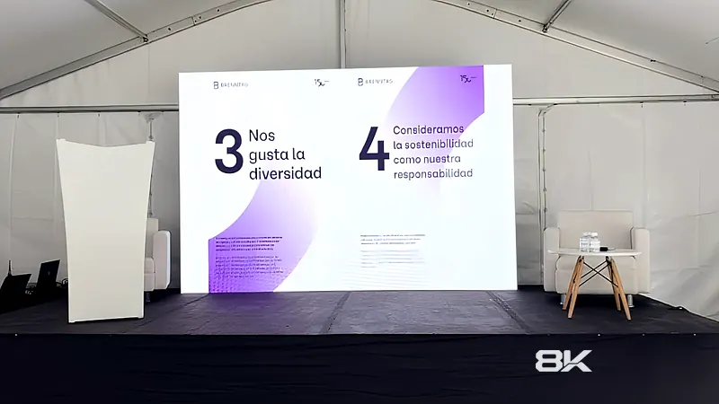 Tarima con pantalla LED y sillas para conversatorio dentro de una carpa en un evento corporativo