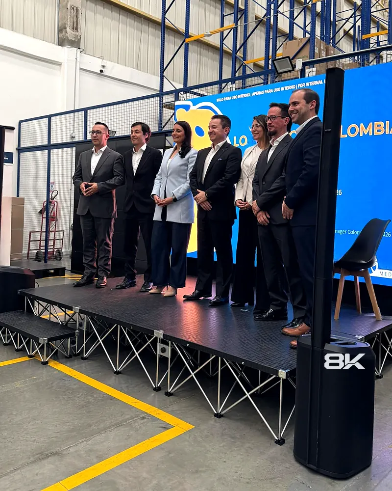 Directivos sobre una tarima con pantalla LED al fondo en un evento corporativo