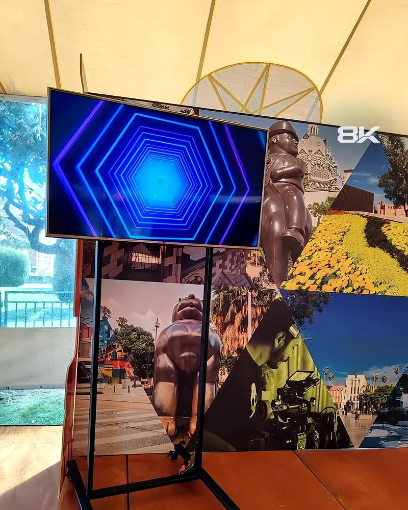 Televisor sobre soporte de piso con ruedas en un stand con fondo fotográfico de Medellín